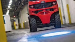 Linde counterbalance forklift truck with BlueSpot projects a blue warning dot onto the warehouse floor