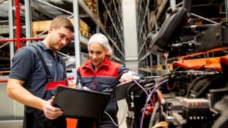 Two Linde Material Handling service technicians look at a laptop next to a truck.
