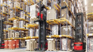 Two Linde Material Handling very narrow aisle trucks in use in a high shelving warehouse.