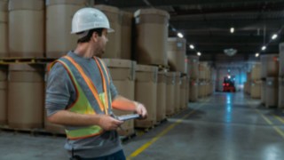 Interactive warning vest from Linde Material Handling improves safety standards Warehouse worker wearing an interactive warning vest from Linde Material Handling in a poorly lit warehouse