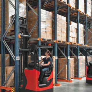 Various assistance systems make the use of Linde reach trucks more efficient as well as safer. Two Linde reach trucks in use on a rack.