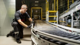 A service technician from Linde MH repairs a roller conveyor