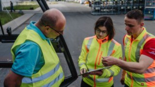 Three people with high-visibility vests in conversation: safety consulting on site at the customer’s premises. Three people with high-visibility vests in conversation: safety consulting on site at the customer’s premises.
