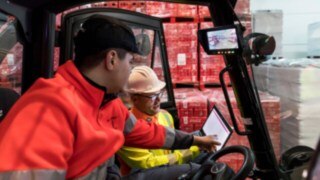 Safety expert from Linde MH shows a forklift operator data on a tablet. Safety expert from Linde MH shows a forklift operator data on a tablet.