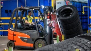 A Michelin Tyre PLC employee moves a stack of tires using a Linde E20 with a tire clamp.