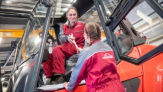 Our employees play a central role in our sustainability policy. A service technician hands a tool to another service technician in a forklift truck.