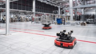 Autonomous transport robots in a modern logistics hall represent cutting edge technology, intelligent automation solutions and the innovative corporate culture at KION.