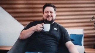 An employee with a coffee cup in his hand looks relaxed and friendly while actively working in commissioning at Linde. 