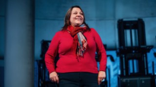 A sales employee stands confidently in front of a row of modern Linde industrial trucks, symbolising customer proximity, enthusiasm for innovative solutions and the global impact of successful sales work. 