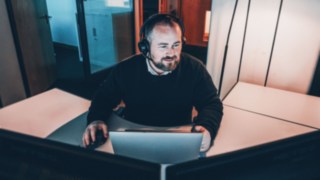 A project manager works intently on his laptop, symbolizing the coordination of complex projects, from the initial idea to implementation at the customer's site.