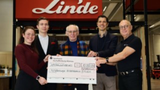 Donation from the StaplerCup hilft e. V. to Aschaffenburger Kinderträume Five people stand together holding a large cheque addressed by Linde MH to Aschaffenburger Kinderträume for the sum of 10,000 euros.