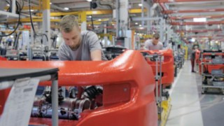 Our platform concept with mixed assembly allows us to conserve resources efficiently. Factory mechanics working on a row of Linde trucks.